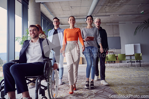 Image of A diverse group of businessmen, including a businessman in wheelchair, confidently stride together through a modern, spacious office, epitomizing collaboration, inclusivity, and strength in unity