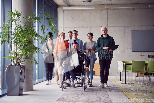 Image of A diverse group of businessmen, including a businessman in wheelchair, confidently stride together through a modern, spacious office, epitomizing collaboration, inclusivity, and strength in unity