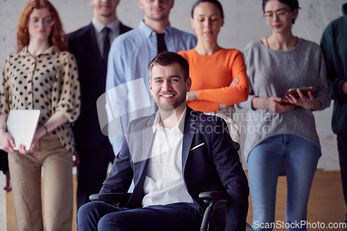 Image of Diverse group of business people, including a businessman in a wheelchair in a modern office