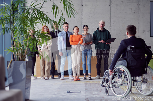 Image of A group of diverse entrepreneurs gather in a modern office to discuss business ideas and strategies, while a colleague in a wheelchair joins them.