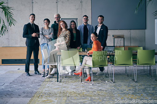 Image of A diverse group of successful businesspeople gather and pose for a photo, showcasing teamwork and professional empowerment in a modern office setting.