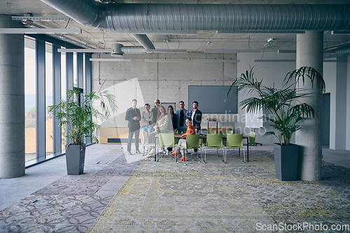 Image of A diverse group of successful businesspeople gather and pose for a photo, showcasing teamwork and professional empowerment in a modern office setting.