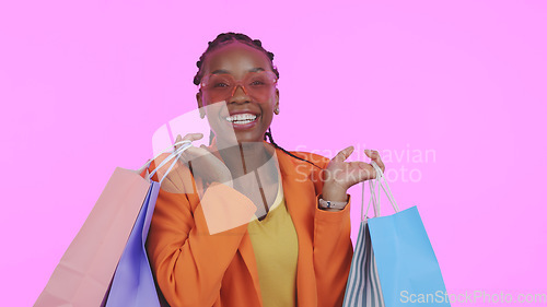 Image of Happy woman, shopping bag and sunglasses for fashion sale, discount and giveaway or retail celebration in studio. Excited portrait of african customer in heart accessories or style on pink background