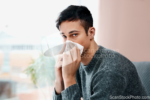 Image of When flu season starts up so does my allergies. a young man blowing his nose while recovering from an illness in bed at home.