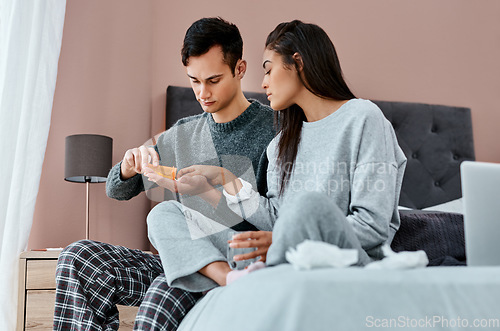 Image of Making the journey to recovery a joint one. a young couple taking medication while recovering from an illness in bed at home.