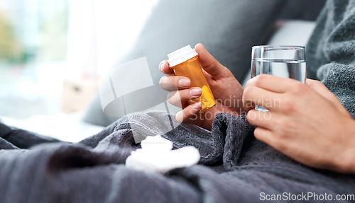 Image of Keep your fluid intake up and your exertion levels low. an unrecognisable man taking medication while recovering from an illness in bed at home.