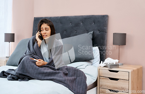 Image of House calls look a bit different these days. a young woman using a smartphone and thermometer while recovering from an illness at home.