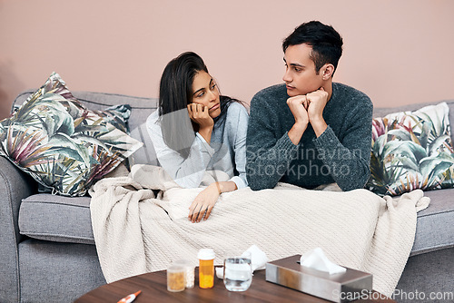 Image of Self quarantine can lead to feelings of stagnation. a young couple sitting on the sofa while recovering from an illness at home.