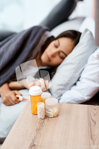 Image of Every pill for every symptom possible. a young woman recovering from an illness in bed at home.