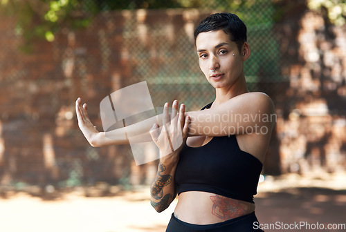 Image of Going through her warmup routine. Cropped portrait of an attractive young female athlete stretching while standing on the basketball court.