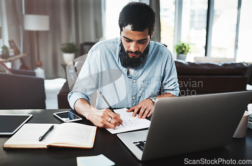Image of He mastered working from home effectively. a young man making notes while busy working from home.