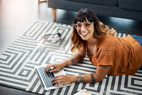 Image of Im writing another post for my blog. a young woman using her laptop while relaxing at home.