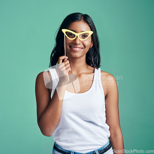 Image of Now Im stylin. Studio portrait of a beautiful young woman posing with prop glasses against a green background.