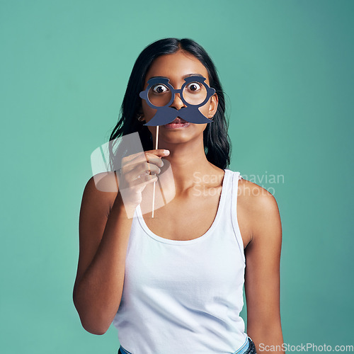 Image of No one will recognise me now. Studio portrait of a beautiful young woman posing with prop glasses against a green background.