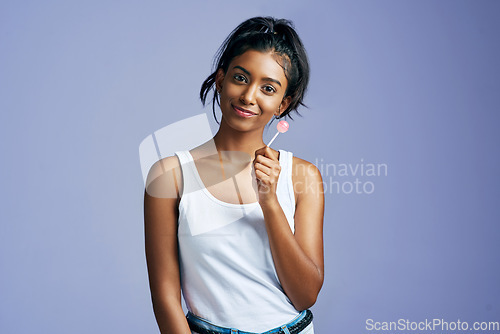 Image of Sweet things just make me sweeter. Studio portrait of a beautiful young woman sucking on a lollipop against a purple background.