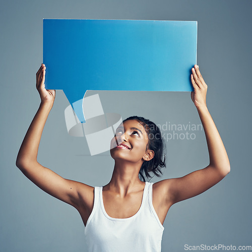 Image of Say what youve gotta say. Studio shot of a beautiful young woman holding up a blank signboard against a grey background.