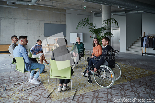 Image of In a modern office, a diverse group of business individuals is seen gathered in a circle, engaged in lively discussions and sharing ideas about various business concepts.