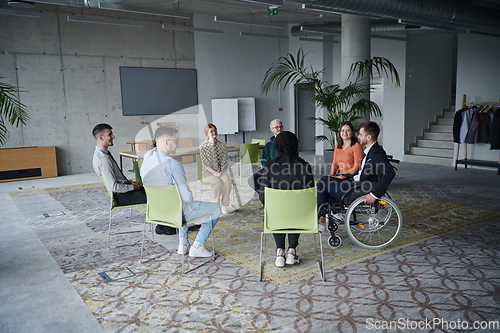 Image of In a modern office, a diverse group of business individuals is seen gathered in a circle, engaged in lively discussions and sharing ideas about various business concepts.