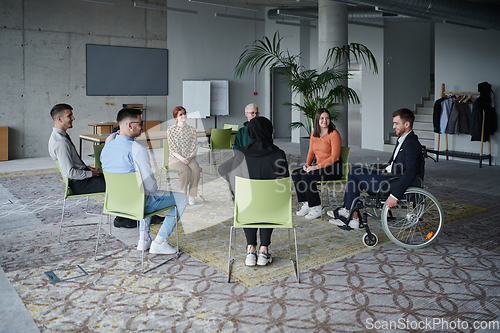 Image of In a modern office, a diverse group of business individuals is seen gathered in a circle, engaged in lively discussions and sharing ideas about various business concepts.