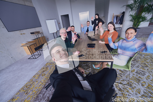 Image of In a modern office, a group of businessmen gathers around a table during a meeting, capturing a moment of camaraderie and teamwork as they take a selfie