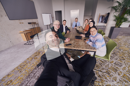 Image of In a modern office, a group of businessmen gathers around a table during a meeting, capturing a moment of camaraderie and teamwork as they take a selfie