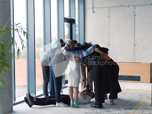 Image of Offstage. The photographer takes a photo of a diverse group of businessmen in a modern office who hug each other in a circle