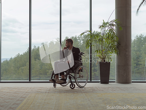 Image of A melancholic businessman in a wheelchair sitting with a sad expression, gazing through the window of a modern office, conveying a sense of solitude