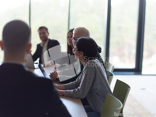 Image of A diverse group of business professionals, including an person with a disability, gathered at a modern office for a productive and inclusive meeting.