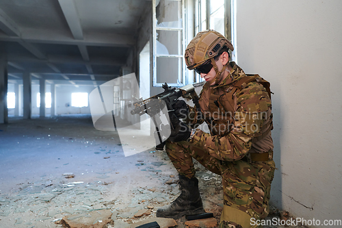 Image of Soldier in action near window changing magazine and take cover