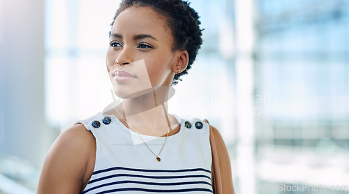 Image of Big plans in that beautiful mind. an attractive young businesswoman looking thoughtful while standing in a modern office.