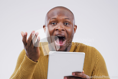 Image of I have no idea how I won this online competition. Studio shot of a young man looking surprised while using a digital tablet.