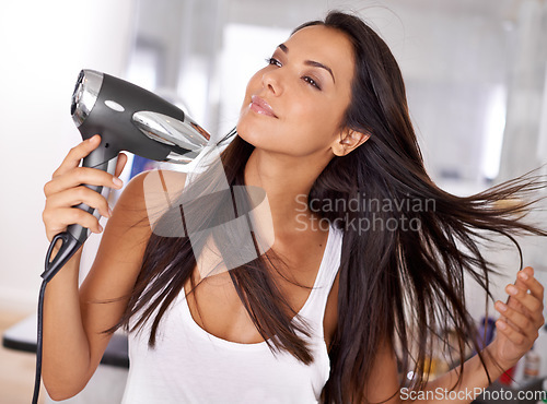 Image of Nothing like the feeling of wind in your hair. a beautiful young woman blow drying her hair.