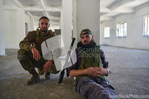Image of Group of soldiers discusses military tactics while situated in an abandoned building, meticulously planning their moves with focus and determination.