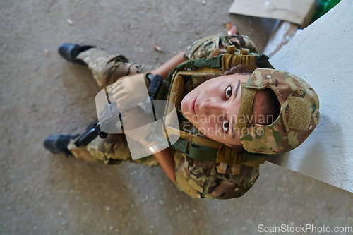 Image of A woman in a professional military uniform sits in an abandoned building, ready for a dangerous mission, exuding bravery and determination
