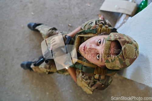 Image of A woman in a professional military uniform sits in an abandoned building, ready for a dangerous mission, exuding bravery and determination