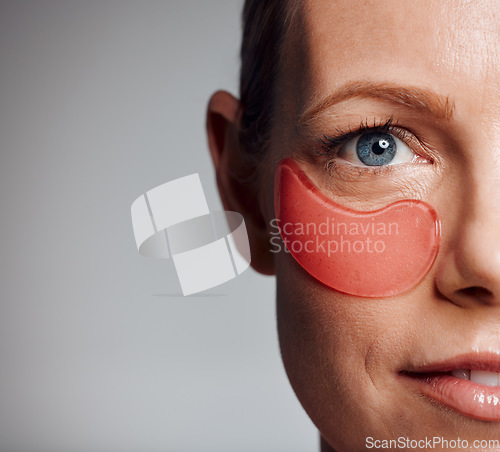 Image of Beautiful mature woman posing with under eye patch in studio against a grey background