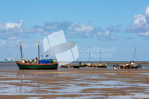 Image of Fishing boat stranded on the dry port during low tide with Malagasy people around.