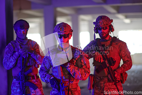 Image of Soldier squad team walking in urban environment colored lightis