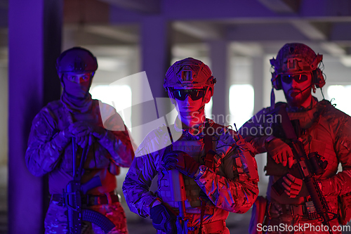 Image of Soldier squad team walking in urban environment colored lightis