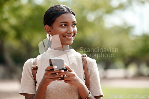 Image of Progress happens when you keep your thoughts positive. a young businesswoman using a smartphone against a city background.