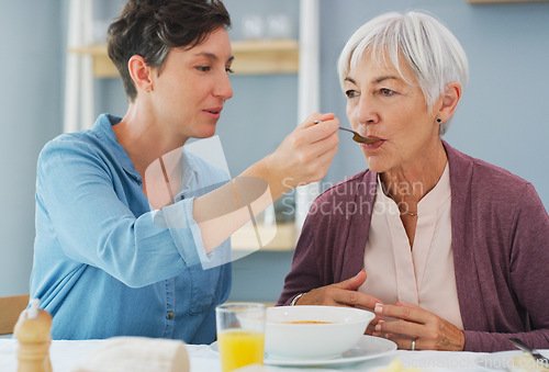 Image of Isnt this delicious Mum. an attractive young woman helping and feeding her senior mother while they have breakfast together at home.