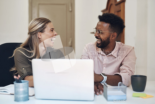 Image of Things keep getting better and better for them. two businesspeople laughing while working together in an office.