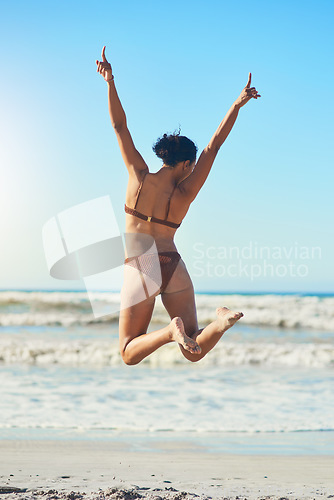 Image of Nothing beats a sunny day on the beach. Rearview shot of a young woman standing on the beach.