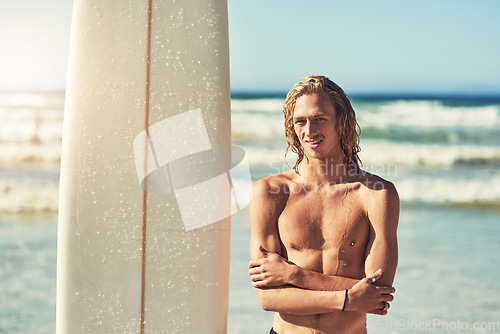 Image of Being a surfer makes you seem cooler. a handsome young man at the beach with his surfboard.