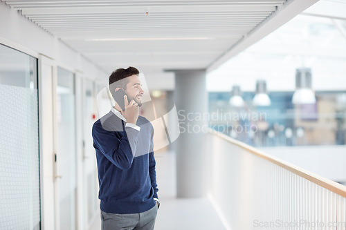 Image of Stepping out to make a follow-up call with a client. a young businessman talking on a cellphone in an office.