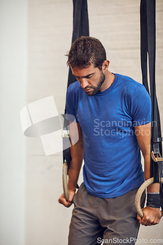 Image of Training hard to get the results he wants. a handsome young man working out on gymnastics rings in the gym.