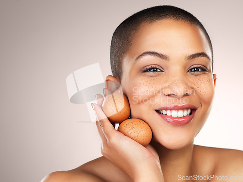 Image of The high protein content help in repairing tissues and firming skin. Studio shot of a beautiful young woman holding eggs against her face.