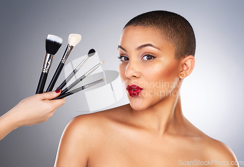 Image of Theres a wand for every kind of magic. Studio shot of a hand holding makeup brushes next to a beautiful young womans face.