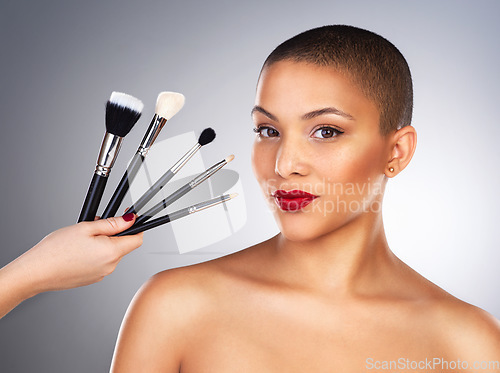 Image of Not every artist uses paper and paint. Studio shot of a hand holding makeup brushes next to a beautiful young womans face.