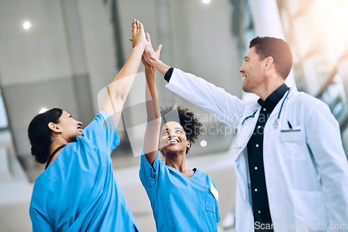 Image of We save lives when we work together. a diverse team of doctors giving each other a high five in a hospital.